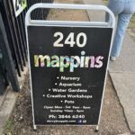 A sign for Mappins is displayed on a sidewalk.
