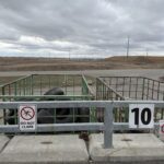 A sign warns against climbing a fence, while a tire is chained to the fence.