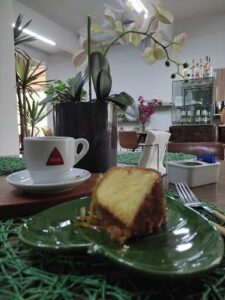 A slice of cake sits on a green plate, accompanied by a cup of coffee.