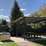 A small outdoor table and bench set up under a tree.