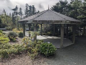A small wooden shelter with a sign in front of it.