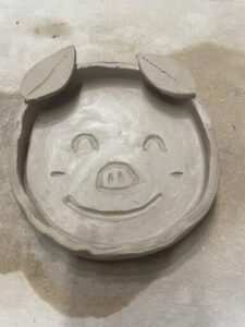 A smiling piggy face made out of clay.