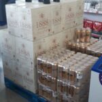 A stack of wine bottles and cans are displayed in a store.