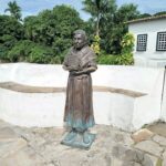 A statue of a woman holding a book is located outside.