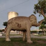 A statue of an elephant is standing in front of a building.