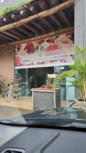 A storefront with a sign that says "Sorria Vo Esto Vendo Flores" and a bicycle parked outside.