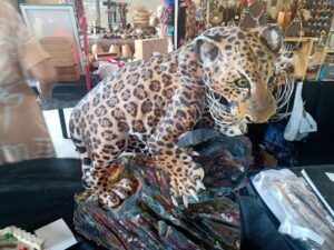 A stuffed leopard sits on a wooden table.