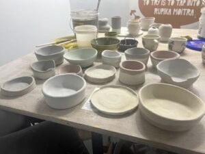 A table full of bowls and cups, some of which are white and pink.