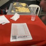 A table with a sign that says "Tabela de Frango" and a tray of food.