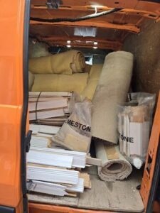 A van is filled with various materials, including a roll of carpet and a bag of insulation.