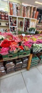 A variety of flowers are displayed in a store, including pink and red roses.