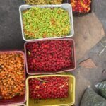 A variety of fruits and vegetables are displayed in multiple baskets, including red peppers, green beans, and yellow squash.