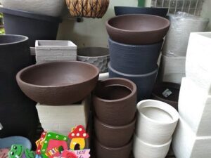 A variety of pots and vases are displayed in a room, including a bowl with a mushroom sticker on it.