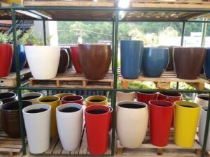 A variety of pots are displayed on a shelf, including blue, red, and yellow ones.
