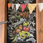 A wall mural featuring a variety of fruits and vegetables, including bananas, apples, and carrots.
