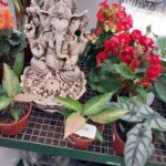 A white statue of a giraffe is sitting in a pot of flowers.