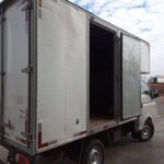 A white truck with a black tarp in the back.