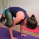 A woman is doing a handstand on a purple mat.