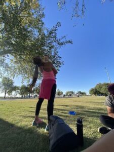 A woman is holding a baby while standing in a park.