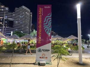 A woman walks past a large sign for a beach resort.