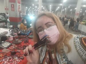 A woman wearing a face mask and glasses is holding a pair of scissors.
