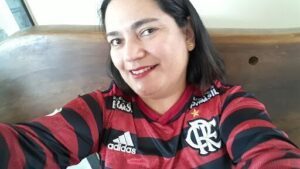 A woman wearing a red and black jersey is smiling for the camera.