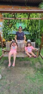 Three little girls sit on a bench, smiling and enjoying their time together.