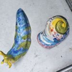 Two colorful sculptures of a snail and a banana are displayed on a table.