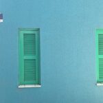 Two green shutters on a blue wall.