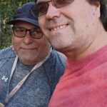 Two men wearing glasses and smiling for the camera.
