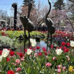 A beautiful garden with a pond and a statue of two birds.