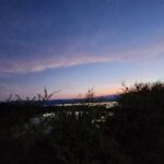 A beautiful sunset over a city skyline, with the sun setting behind a hillside.