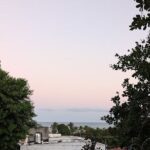 A beautiful sunset over the ocean, with a house and trees in the foreground.