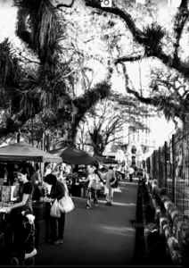 A black and white photo of a busy street with people walking and shopping.