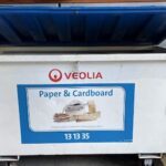 A blue container with a paper and cardboard sign on it.