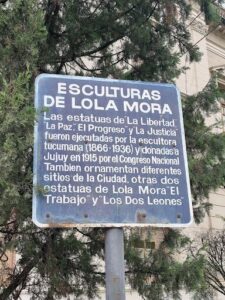 A blue sign with white lettering is posted on a pole.