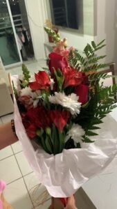 A bouquet of red and white flowers is held by a person.