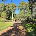 A brick walkway leads to a wooden structure in a park.