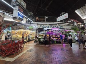 A bustling marketplace with people shopping and a variety of items for sale.
