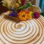 A cake with a wooden stick and a flower on top.