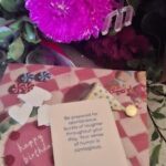 A card with a pink flower on it reads "Be prepared for spontaneous bursts of love through your sense of humor is contagious."