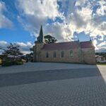 A church with a steeple and a cross on top of it.
