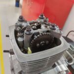 A close up of a motorcycle engine with the cover off, revealing the internal components.