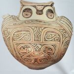 A close up of a pottery piece with a face on it.