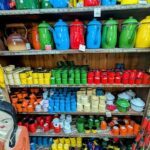 A colorful display of various containers, including pots, pans, and vases, are arranged on a wooden shelf.