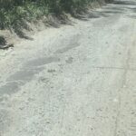 A dirt road with a grassy hillside.