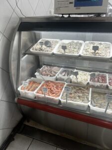 A display case filled with various seafood items, including shrimp, crab, and lobster.