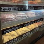A display case filled with various types of meat, including sausage and pork, is labeled with prices.