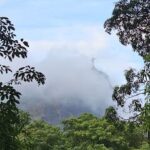 A foggy mountain with a statue of Christ on top.