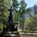 A fountain in a park with a statue of a woman and a tree in the background.